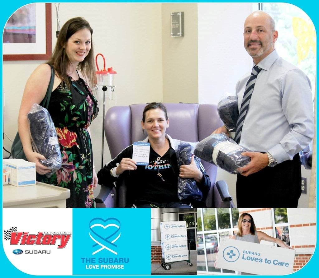 Three people in a medical setting, two bringing blankets to a patient, with Subaru Love Promise branding below.