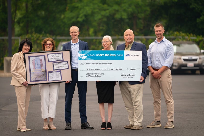 Five people hold an oversized check for $39,839 and a framed painting from the Center for
Great Expectations.