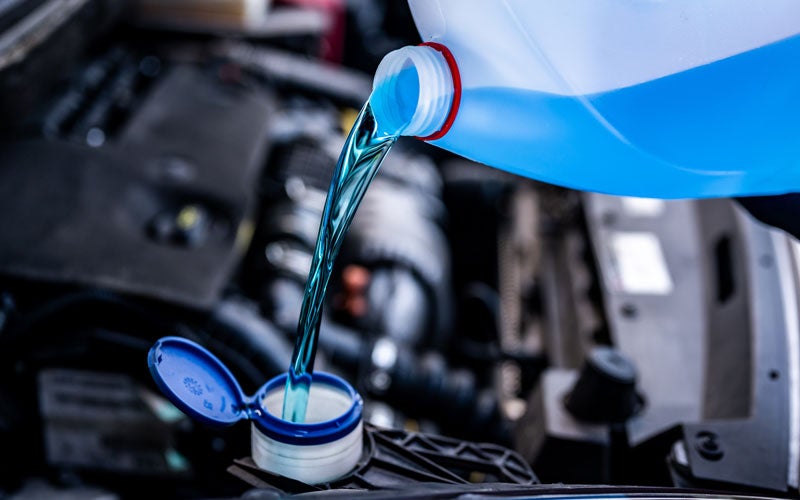 Blue engine coolant being poured into a vehicle reservoir