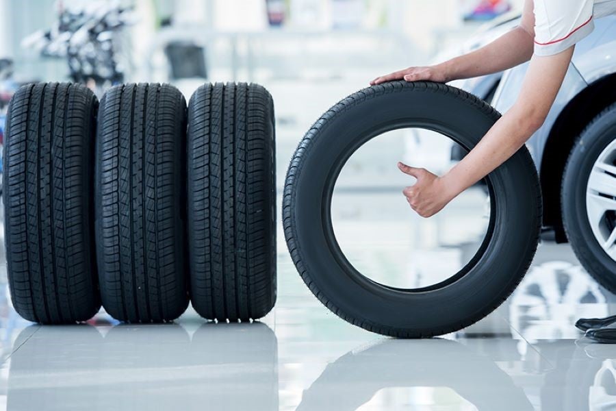 Person giving a thumbs up through a new car tire